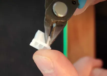 A close-up of a person cutting a small piece of wireDescription automatically generated