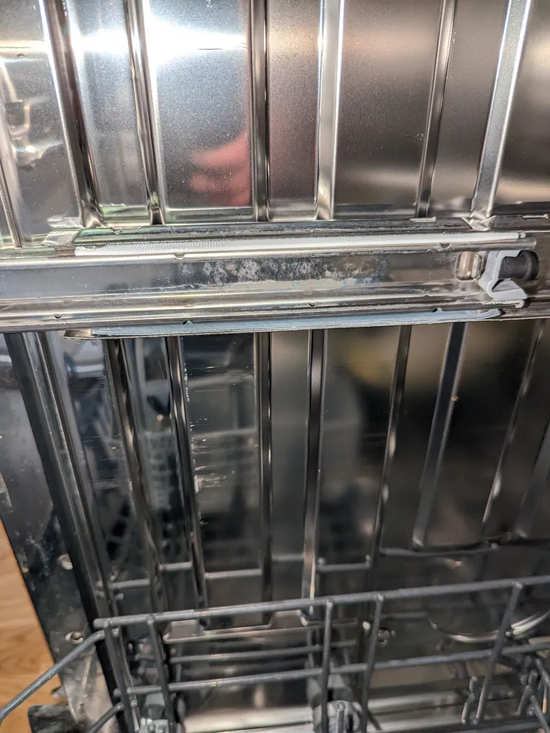 Dishwasher distance spacer between rail and top rack