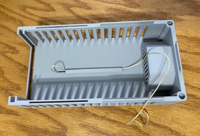 A grey plastic container with a string attached to it
Description automatically generated
