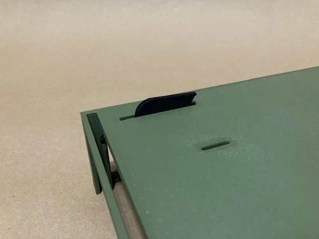 A close-up of a green metal piece
Description automatically generated