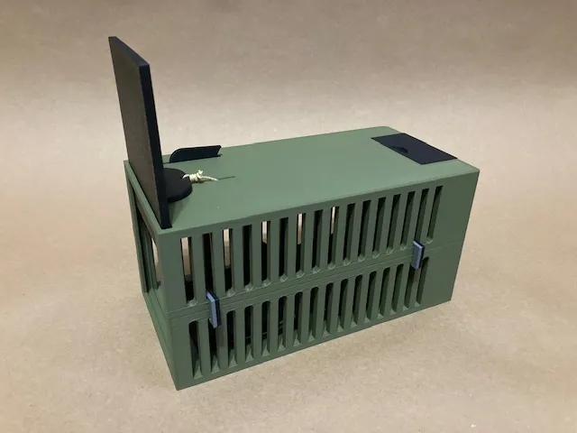 A green cage with a black object on top