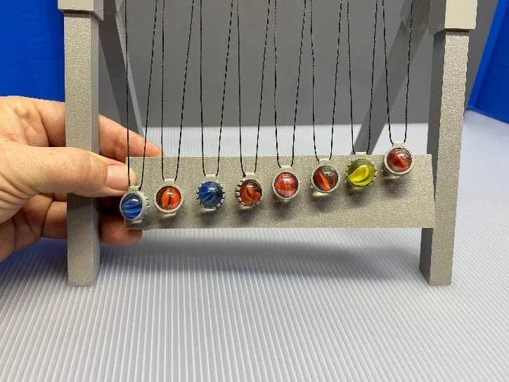 A hand holding a pendulum
Description automatically generated