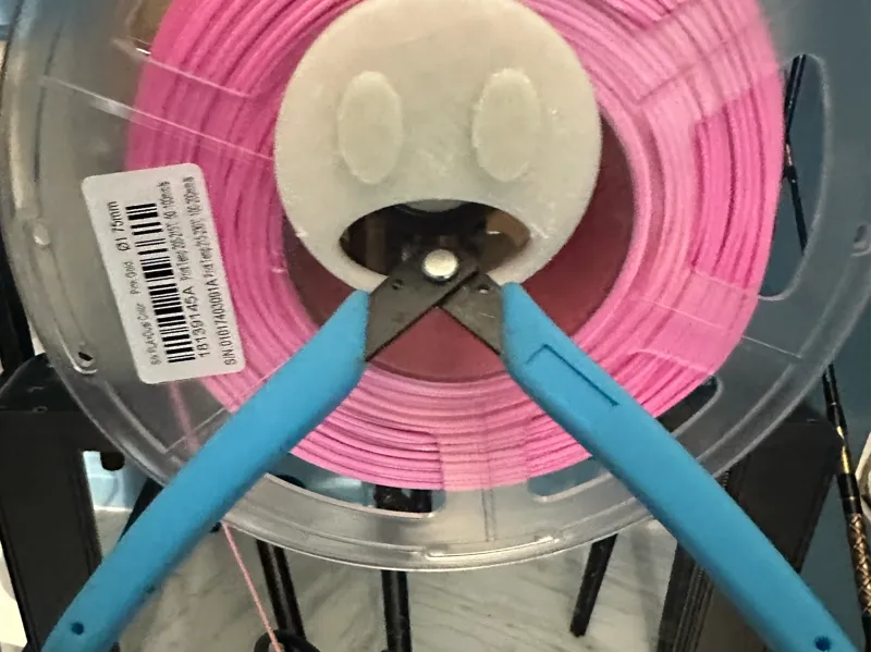 Shocked emoji that holds cutting pliers