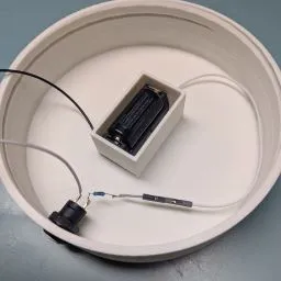A small white box with wires in it

Description automatically generated