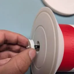 A hand holding a small white and red object

Description automatically generated