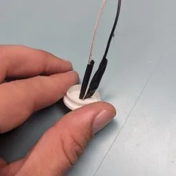 A person holding a small white object with wires

Description automatically generated