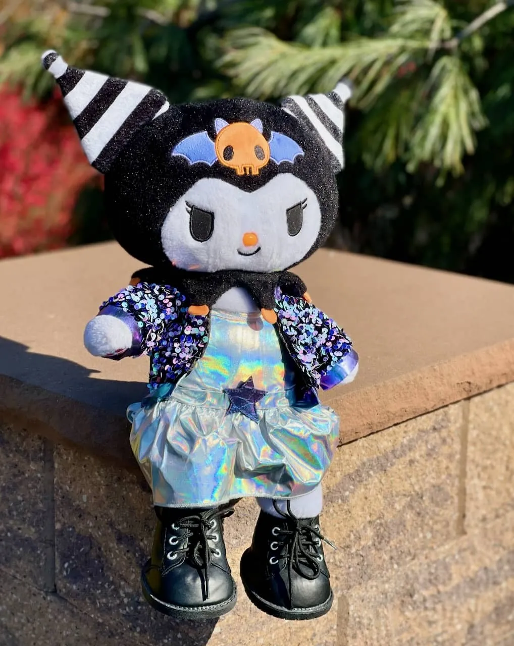 Build-a-bear Kuromi wearing a glam sequined jacket and iridescent dress, with faux-steel-toed, faux-leather boots.