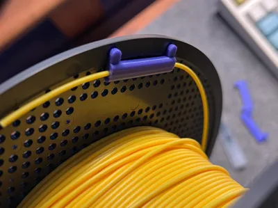 A dedicated filament clip for Bambu Lab original filament spools, usable to secure filament during AMS2 PRO drying to prevent spool explosions