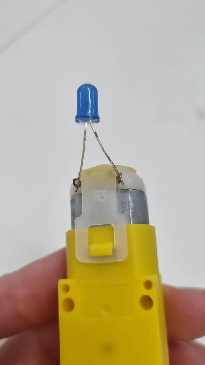 Solder the LED's terminals, one to each motor terminal. There's no right or wrong way to solder here; reversing the LED's polarity only changes the direction you need to turn the handle for it to light up.