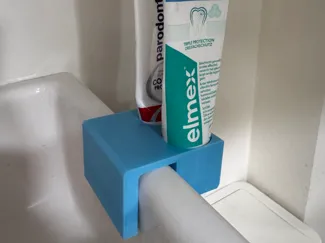 Toothpaste holder for bathroom sink