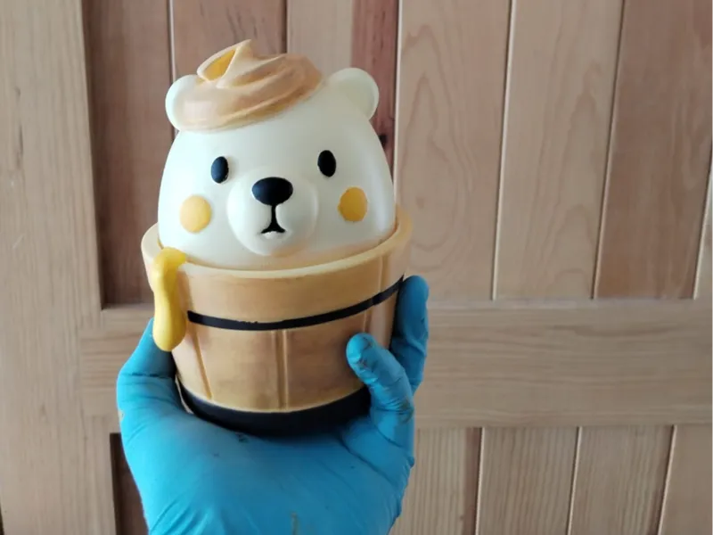Little bear coming out of a honey bucket