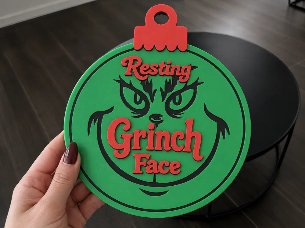 Letrero o emblema decorativo: Resting Grinch Face Christmas Bauble Decor 2 Sizes. Referencia del modelo original.