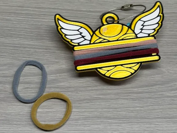 Accesorio para sujetar ligas de cabello: Golden Snitch Hair Tie Holder Keychain. Referencia del modelo original.