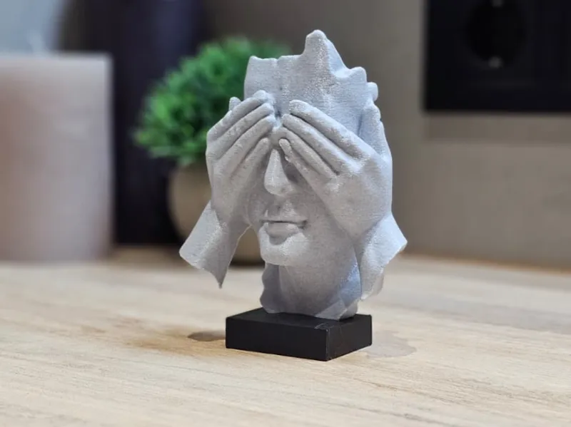 Escultura fragmentada con manos cubriendo los ojos