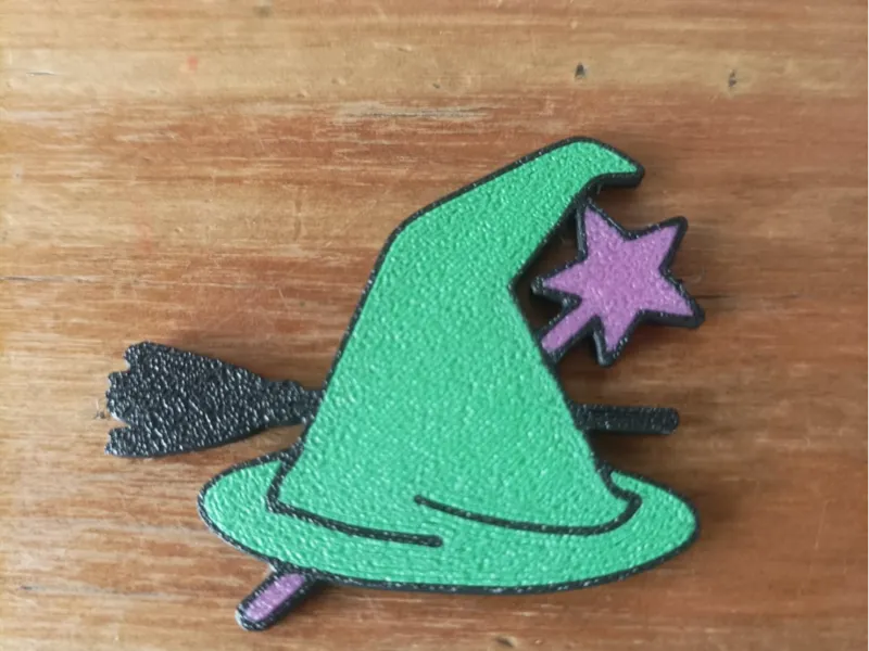 Prendedor de gorro de bruja con varita y escoba