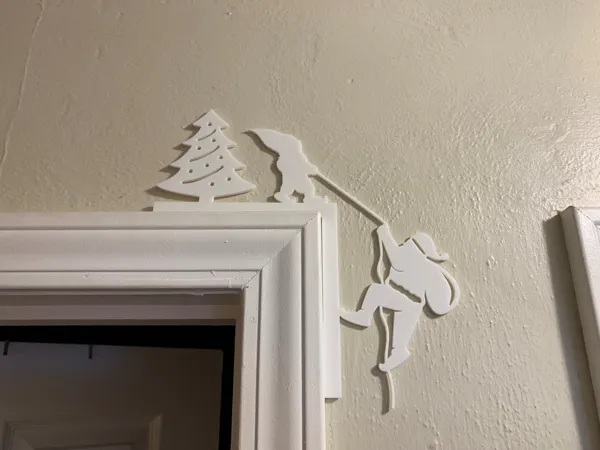 Père Noël grimpant au coin de la porte