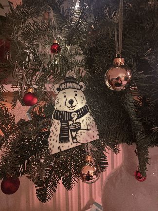 Two-colored Christmas tree decoration polar bear with coffee in hand
