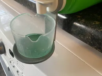 Dispensing cup holder for detergent bottles
