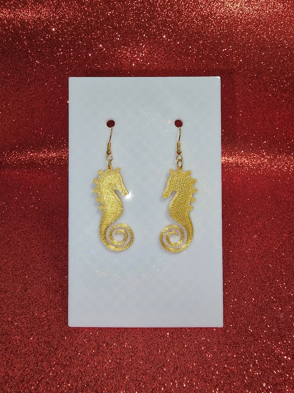 A gold seahorse earring view 2