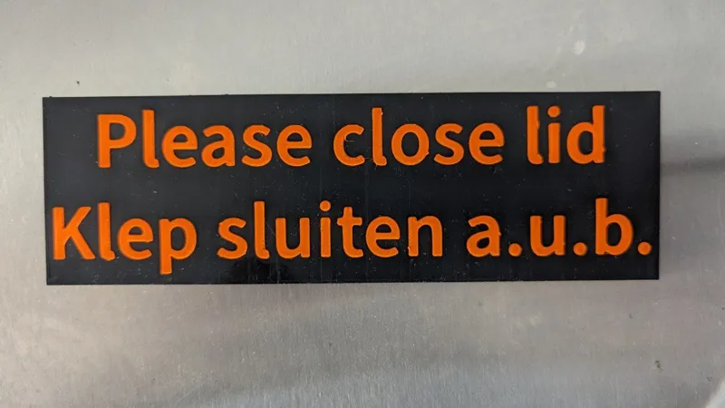 'Please close lid' sign / 'Klep sluiten a.u.b.' bordje
