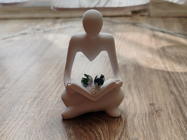 Figurine of a woman reading with flowers